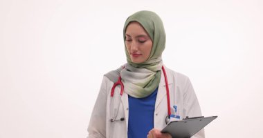 Tesettürlü kadın doktor beyaz arka planda tıbbi belge ve ultrason cihazı tutuyor. Doktor muayeneye başlamak için hazırlanıyor. Yavaş çekim