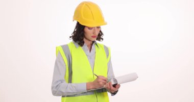 Odaklanmış kadın mühendis beyaz arka plan üzerine notlar yazıyor. İş yerindeki projeyle ilgili sabit şapka ölçümleri yapan kadın müfettiş.