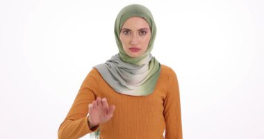Müslüman kadın beyaz arka planda el kaldırıyor. Türbanlı ciddi kadın, protesto sırasında aile içi şiddet ve sosyal adaletsizliğe son verilmesini istiyor