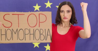 Ciddi kadınların elinde Avrupa Birliği bayrağına yumruk sallamayı bırak işareti var. Kadın eylemci toplumsal hoşgörü sorunlarını gündeme getiriyor