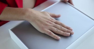 Resmi giyinen iş kadını kutuyu açar ve masadaki iPad 'i çıkarır. Kadın ofis çalışanı nazikçe modern aygıtı elleriyle paketlemeden kaldırdı