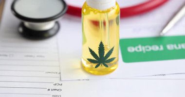 Belgelerin üstüne marihuana yaprağı sembollü sarı sıvı damlatıcıyla cam şişe. Tıbbi marihuana ve alternatif tıbba odaklanın.