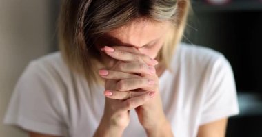 Kadın derin duygusal sıkıntı içinde, elleri bağlı ve başı eğik. Yüz ifadesi ve vücut dili umutsuzluk anında dua ettiğini gösteriyor.