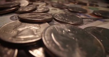 İçinde Benjamin Franklin 'in portresi ve sayısız madeni para olan banknotlar. Yüzeye saçılmış para Amerikan para birimine odaklanmamızı öneriyor.