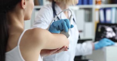 Mavi eldivenli tıbbi uzman kadın dirseğinde ultrason ameliyatı yapıyor. Klinik muayene ortamındaki hastalar için ultrason kontrolleri