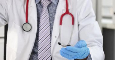 Beyaz önlük ve steteskop giyen doktor eldivenli ellere antiseptik uygular. Hastayı muayene etmeden önce antiseptik kullanan erkek ellerine odaklan.