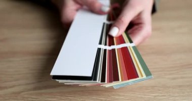 Kadının elinde ahşap masanın üzerinde yelpaze demeti var. Örnekler, iç dekorasyon için seçim sürecini öneren geniş renk yelpazesini gösterir