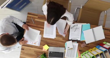 Erkek ve kadın ofis çalışanları önümüzdeki sunum için önemli belgeleri gözden geçiriyorlar. Deneyimli çalışanlar düzeltme raporlarını karşılaştırır