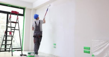 İnşaat işçisi duvara pürüzsüz boya sürmek için paten kullanır. İnşaatçı alçıyı temiz ve profesyonel bir şekilde bitirmeye çalışıyor. Yavaş çekim