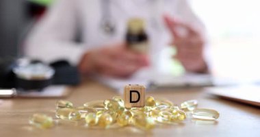Beyaz önlüklü doktor D vitamininin küpteki faydalarını tanımlıyor. Doktor, hastaya düzenli olarak D vitamini almanın önemini anlatır. Yavaş çekim