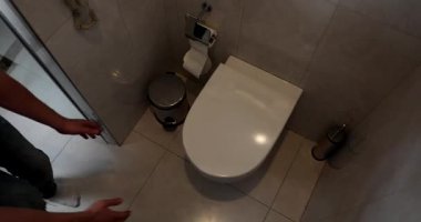 Adam dengesiz adımlarla tuvalete ulaşır ve kusmak için elleri titreyerek kapağı kaldırır. Ter içinde erkek yüzü. Adamın midesi çok bulanıyor.