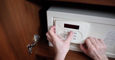 Adam otelin kasasında duruyor ve şifreyi basamaklı tuşlarla girmeye başlıyor. Erkek tuşlara basar ve kilidi açan mekanizmanın yumuşak tıklamasını dinler