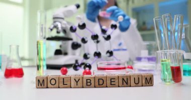 Kendini işine adamış bir bilim adamı renkli ve canlı bir laboratuvar ortamında molibdenum üzerinde çeşitli deneyler yapıyor.