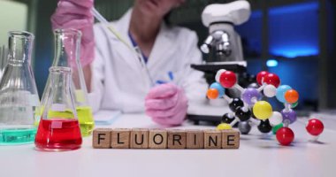 Bir bilim adamı bir laboratuarda florin araştırması yapıyor, pipetleri ve çeşitli cam parçalarını kullanıyor.