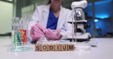 Bir bilim adamı laboratuvarda sodyumu inceliyor, kapsamlı analiz ve araştırma için test ve ekipman sergiliyor.