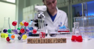 Kendini işine adamış bir bilim adamı, rubidyum örnekleri ve renkli moleküler modelleri incelemek için bir laboratuvarda özenle çalışıyor.