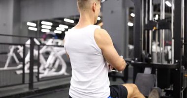 Genç kaslı erkek sporcu spor salonunda güçlü sırt ve kollarıyla kürek çekiyor. Yoğun çalışma gücü ve kas gelişimine odaklandı