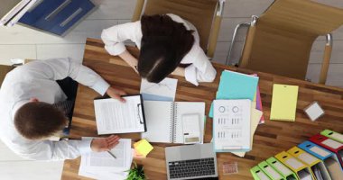 İş arkadaşları ofis masasının üst katında sözleşmeyi tartışıyor. Kadın asistan, şirket işyerindeki erkek ortağına anlaşma belgesi gösterdi