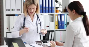 Doktor, klinik konsültasyon sırasında hastayla göğüs implantı ameliyatını tartıştığını gösteriyor. Cerrah kadına büyütmeyi açıklıyor