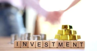 İşadamları el sıkışırken, altın külçeler ve madeni paralar, bloklar halinde yatırımla birlikte masaya dizilmiş. Finansal ortaklığın simgelemesi