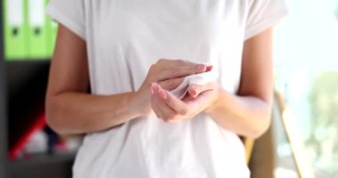 Bayan ofis çalışanı, çalışma ortamında temizlik ve hijyeni sağlamak için ıslak mendille dikkatlice ellerini temizler. Sağlık ve güvenlik uygulamalarının tanıtımı