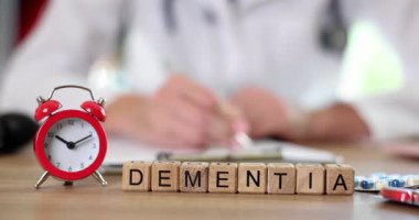 Doktor, Dementia için küplerin tedavisi için çalar saat ve klinikteki masanın üzerine haplar yazıyor. Zamansal tanı ve müdahale önemi