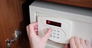 Otel misafiri, elektronik tuş takımına şifre girerek küçük bir kasa açıyor. Turist ziyaretleri sırasında değerli eşyaların güvenli bir şekilde depolanması