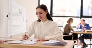 Odaklanmış iş kadını not defterine iş arkadaşlarıyla işbirliği yaptığı ve modern ofiste hoş geldin dediği notlar alıyor. Takım çalışması ve stratejik planlama