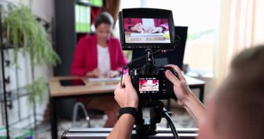 Videograf, iş kadınının masadaki klavyeye yazdığını kaydediyor. Kadın nüfuzlu biri modern ofiste sosyal medya blog videosuna poz veriyor. Ekran görünümü