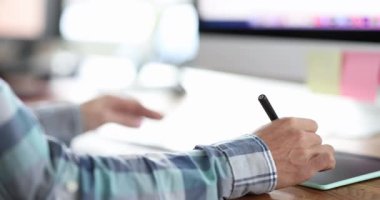 Erkek tasarımcı masa başında resim yapmak için dijital kalem ve tablet kullanır. İnsan eli, ışık ofisindeki modern bilgisayar ekipmanıyla resim çizer