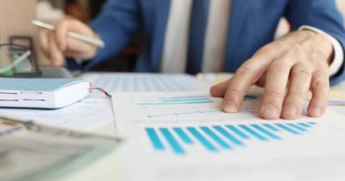 İşadamı, ofiste yatırım kararları alan mali tabloları analiz eder. Uzman, işyerindeki çeşitli faktörleri ve önemli verileri karşılaştırır