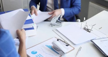 Meslektaşlar sözleşme detaylarını incelerler. Belgeleri ve dosyaları zımbalarlar. Paylaşılan ofis işyerindeki iş sözleşmesi dağınık evraklarla