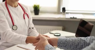 Erkek hasta, elini sıkan kadın hekime teşekkür ediyor. Laboratuvar önlüklü kadın klinikteki başarılı tedavisinden sonra adamın elini sıkıyor.