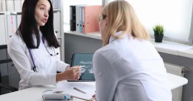 Jinekolog, klinikteki muayene sırasında bebeğin ultrason görüntülerini hamile kadına açıklıyor. Annelik için iletişim ve temel destek