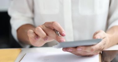 Kadın eli, şirket ofisindeki aylık giderleri sayan hesap makinesine basıyor. Muhasebeci, iş yerinde kapsamlı mali analizler yürütüyor.