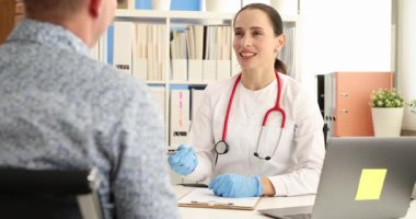 Kadın doktor, klinikteki masada oturan hastaya danışmanlık yapıyor. Adam tıbbi merkezde düzenli sağlık kontrolü için terapiste gidiyor. Sağlık hizmetleri