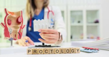 Kadın, Proktoloji ve anatomik rektum modeliyle hemoroit tedavisini Küp yakınlarında inceliyor. Klinikteki hasta bakımı için ilaç fitilleri