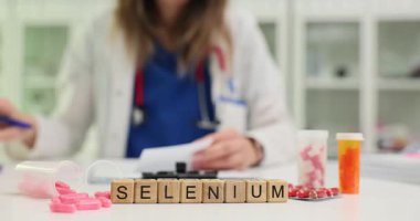 Kadın doktor, muayenehanesinde Selenium bulunan küplerin yakınındaki ilaveler için reçete yazıyor. Hasta sağlığı için vitamin ve minerallerin önemi