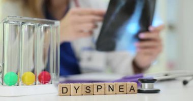 Tahta bloklardan gelen Dyspnea terimi ve doktor masasında bulunan spirometre. Doktor, klinikteki solunum sağlığını kontrol etmek için röntgen görüntüsü tutuyor