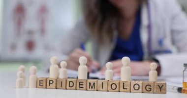 Tahta figürlerin yanındaki küçük bloklardaki salgın hastalık insanları doktorlara karşı gösteriyor. Kadın tıp uzmanı popülasyonlarda hastalık araştırması yapıyor.