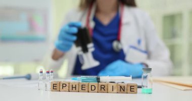 Mavi eldiven giyen profesyonel bir kadın klinikteki küplerde Efedrin ilacıyla çalışan belgeler taşıyor. İlaç ve tıbbi konsept