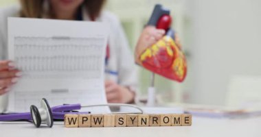 Kadın doktor anatomik kalp modelinin yanında kardiyogram ve WPW Sendromu teşhisi ile tahta küpleri inceliyor. Kardiyolojide analizin önemi