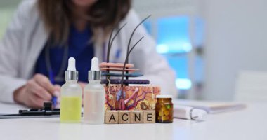 Kadın, masadaki cilt modelinin yanında akne tedavisi için reçete yazıyor. Klinikteki cilt durumları için dermatolojik çözümler