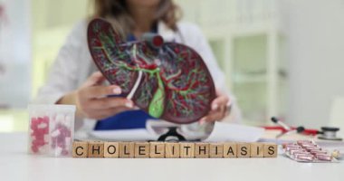 Doktorun klinikte karaciğer modelini sunmasına karşı ahşap küplerden oluşan kolelithias kelimesi. Kadın tıp uzmanı vücut organı hasarı konusunda uyardı