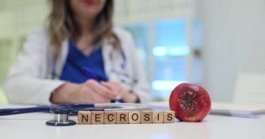 Doktor ofisinde çürük elma ve steteskopla ahşap küplerden yapılmış kelime nekrozu. Hastane çalışanları hasta çizelgesine teşhis koyarlar.