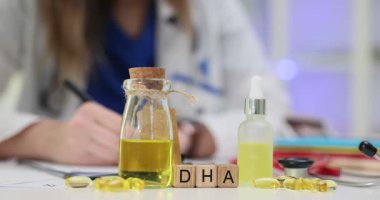 Doktor DHA Omega 3 'ün yanındaki panoya yağ asidi takviyesi üzerine notlar yazıyor. Steteskop yakınındaki muayenede reçeteli bir kadın.