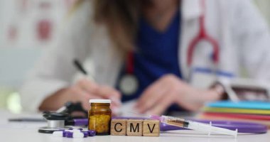 Kadın doktor, CMV tedavisi için ilaç şırıngası ve steteskopla reçete yazıyor. Sitomegalovirüs için sağlık ve tıbbi araştırma