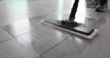 Temizlik işçisi ofiste zemini buharlı paspasla yıkıyor. Buhar temizleme ve dezenfekte parke ile ev ekipmanları
