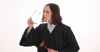 Siyah cüppeli kadın yargıç beyaz arka planda açıkça görmek için gözlük takıyor. Ciddi yargıç yasal otorite ve karar verme yetkisini gösterdi