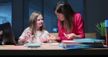 Annem masada oturuyor ve kızına matematik problemini anlatıyor. Ebeveynler çalışma kitabındaki rakamlara işaret ediyor ve çözüme giden yolda liseli kızlara rehberlik ediyor